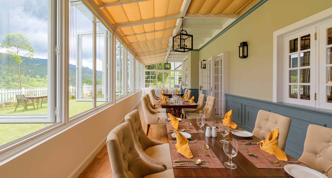 The glazed dining veranda with tables laid along the windows onto the garden