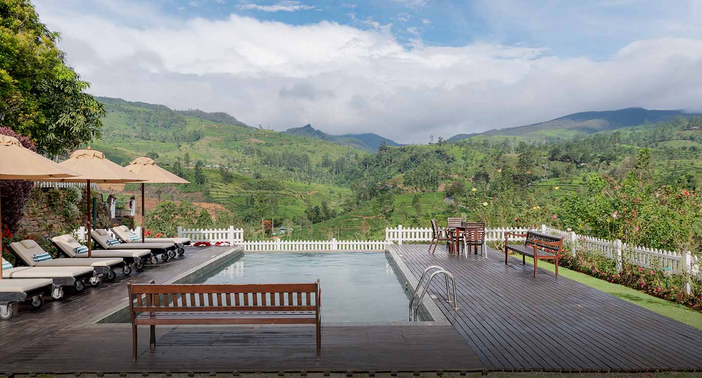 The pool and its timber deck with loungers, looking out over tea to the mountains