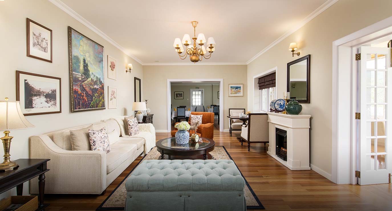 The sitting room with sofas, a fireplace and paintings on pale walls